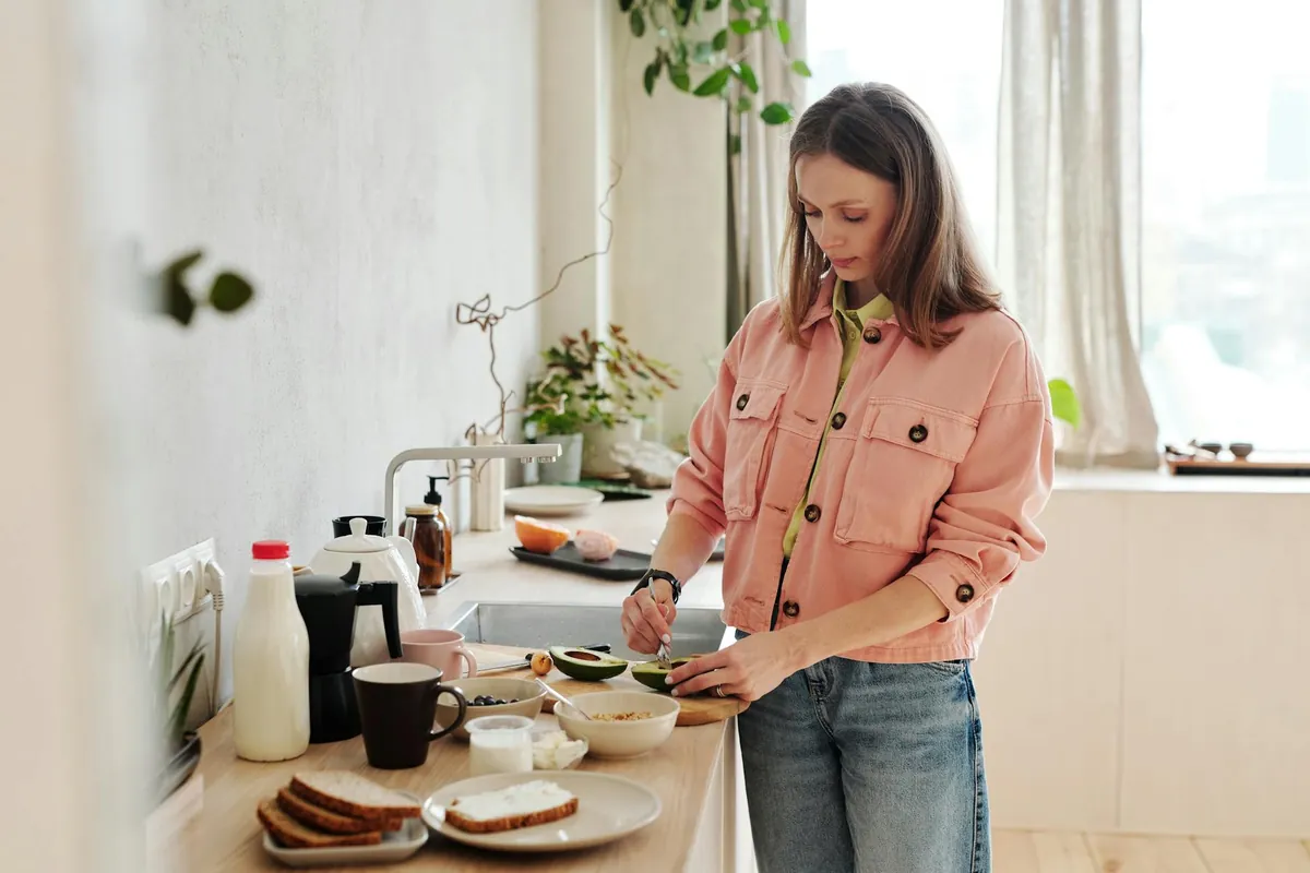 Woman smiling while looking at a plate of colorful, healthy food, representing calorie awareness without strict dieting.