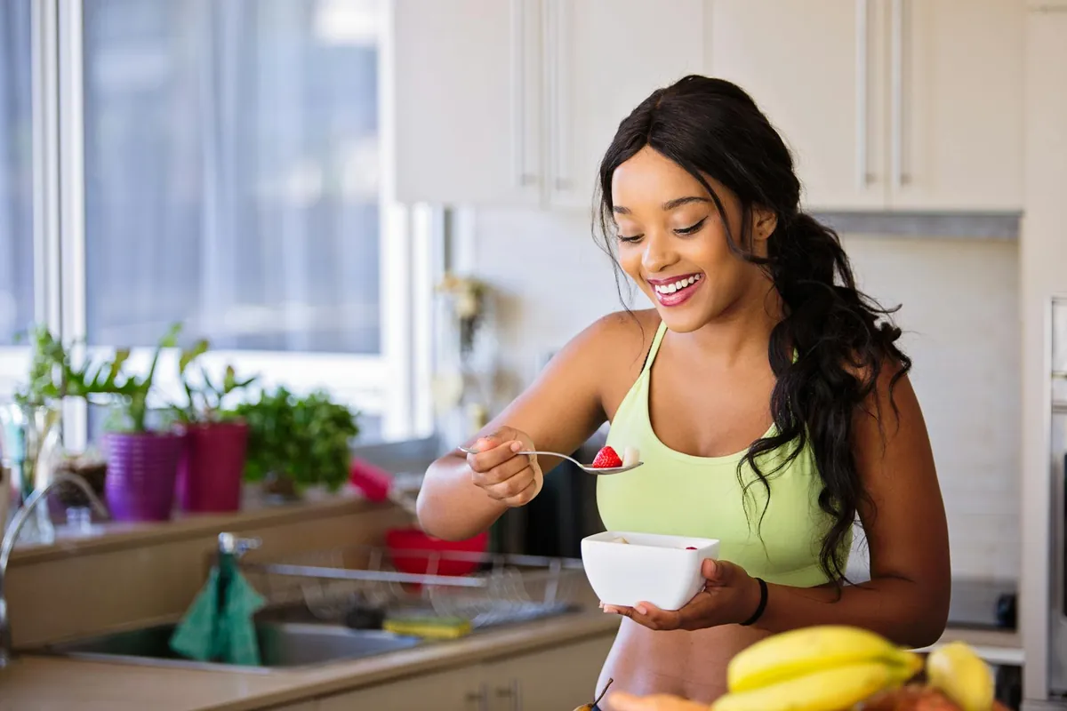 Woman smiling and feeling energetic, holding a healthy snack like an apple with almonds.