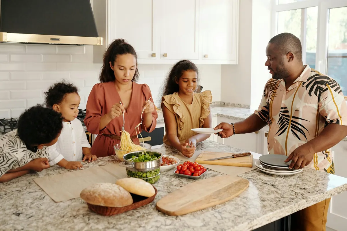 US family smiling while preparing healthy, budget-friendly meals together in their kitchen.