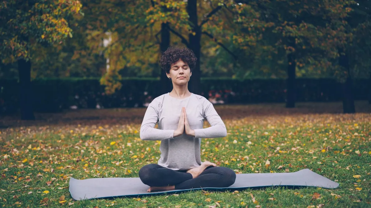 A person sitting peacefully outdoors, practicing deep breathing exercises to manage stress.