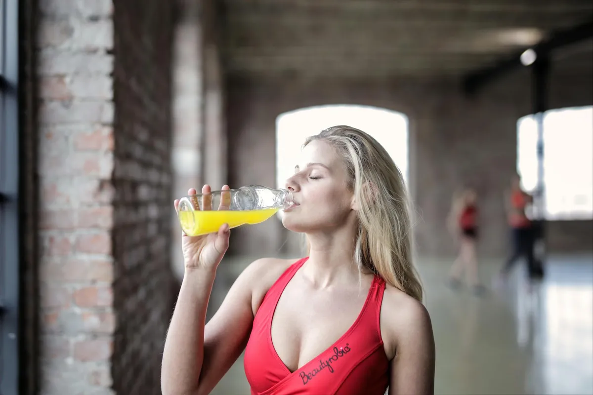 Woman smiling and holding a glass of guava juice, looking refreshed and energetic.