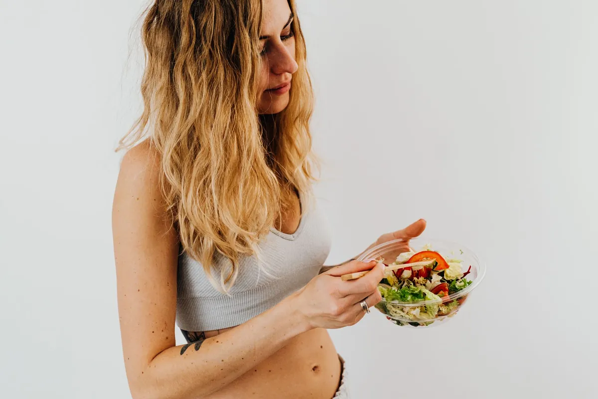 A person happily eating a vibrant, colorful salad, symbolizing good gut health and energy.