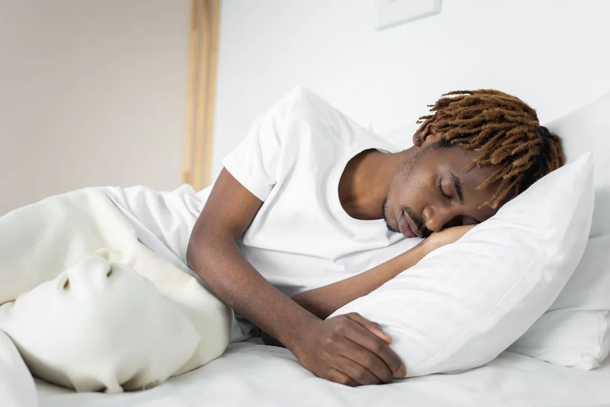 Person peacefully sleeping in a dark, comfortable bedroom.