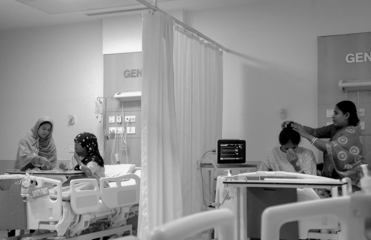 A stressed parent holding hands with a baby in a clinical setting showing support