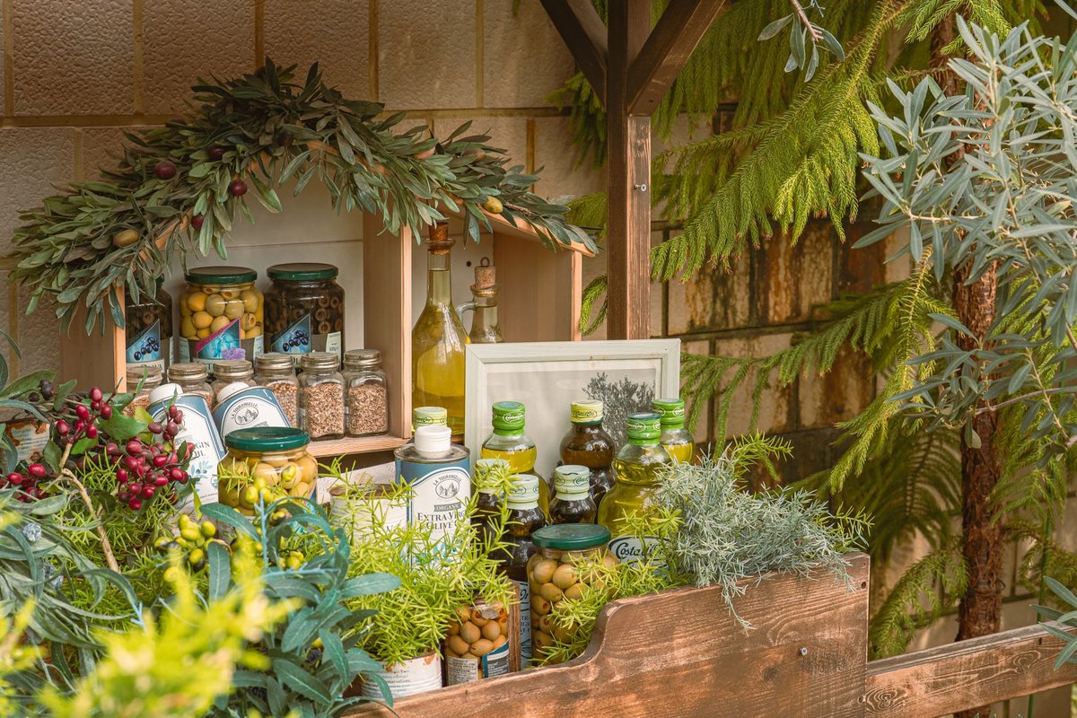 A dark bottle of extra virgin olive oil surrounded by fresh green herbs on a wooden table.