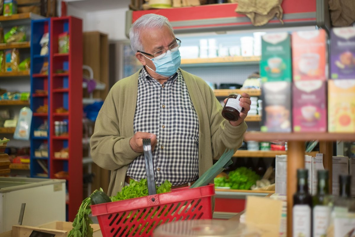 Close up of a person reading the ingredients label on packaged food in a grocery store aisle