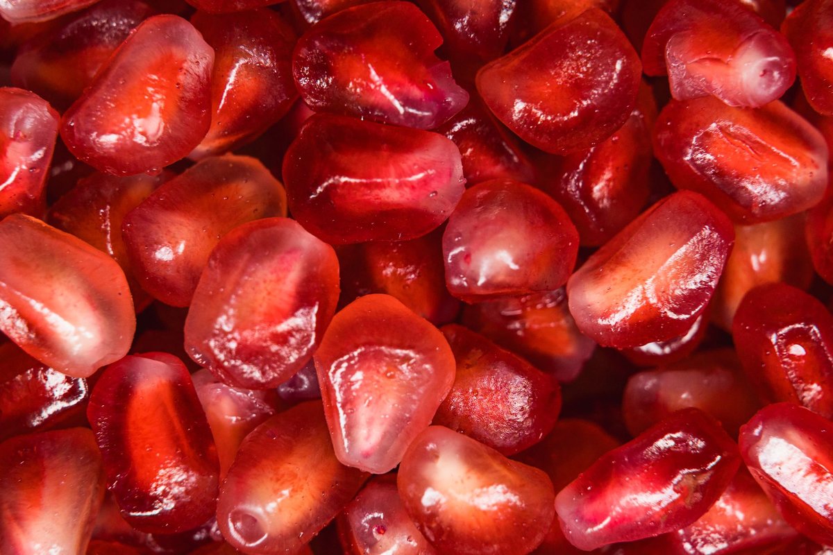 A fresh ripe pomegranate sliced open revealing ruby red seeds on a rustic wooden table