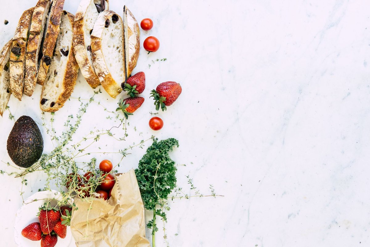 A fresh arrangement of whole foods including colorful vegetables nuts and eggs on a wooden kitchen counter